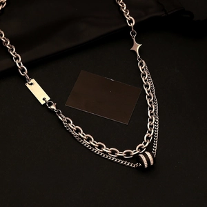 Silver layered necklace with star pendant and striped ring charm on dark fabric
