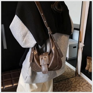 Seitenansicht der braunen Retro-Schultertasche mit Metallschnalle und Nieten am Modell