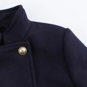 Detail of navy wool coat featuring gold crest buttons and precision shoulder tailoring