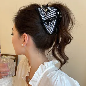 Detail of checkered lace hair tie bow on a ponytail in a warm indoor setting
