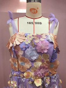 Détail de robe en tulle lavande avec broderie florale 3D colorée et bretelles nouées