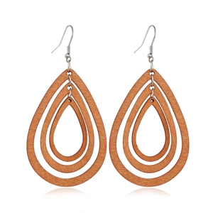 Detailed close-up of brown wooden teardrop earrings with multi-layered hollow geometry