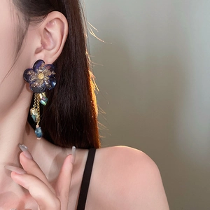 Detail of flower tassel earrings with blue crystals and gold chains on a model