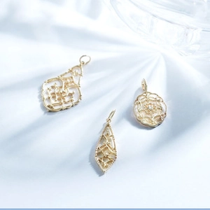 Dettaglio di pendenti vintage in argento 925 con motivi in pizzo e finitura oro