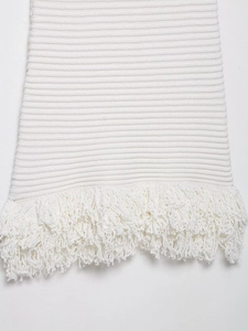 Detail of white knit fabric with elegant fringe hem and textured ribbed pattern