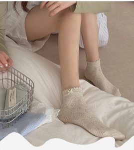 Detail of light beige mesh socks with bow decoration and clover patterns on a model