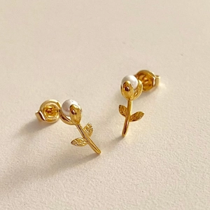 Gros plan sur les boucles d'oreilles tulipes dorées avec perles blanches et gravures