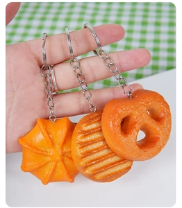 Detailed close-up of PVC pretzel and cookie charms on silver metal keyrings held by hand