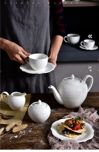 Detail of white embossed ceramic teapot and cups for European style afternoon tea service