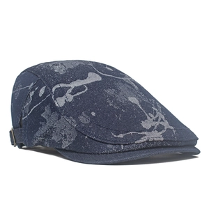 Detail of blue denim flat cap with grey abstract texture and silver metal side buckle