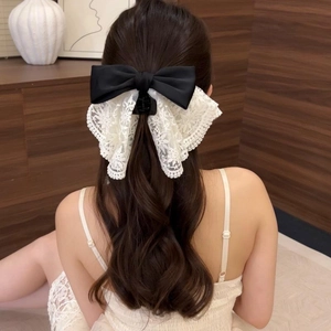 Elegant bow hair claw clip with floral lace detailing worn on a model's half-up hairstyle