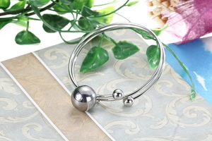 Macro detail of silver stainless steel double coil bracelet with polished metal ball ends