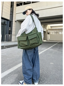 Model showing large army green canvas messenger bag with double pockets and wide strap