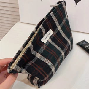 Detail of red and green plaid fabric pouch featuring a zipper and wide interior space