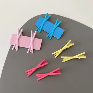 Close-up of X-shaped matte pastel hair clips in pink and blue on a display board