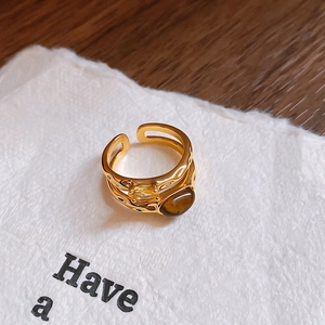 Detailed macro view of textured gold-plated ring with tiger eye and amber-toned stones