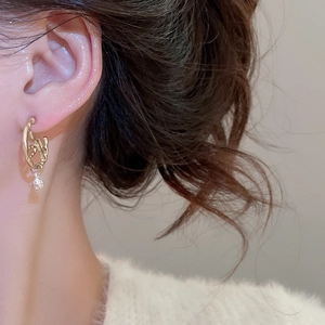 Detailed close-up of golden irregular textured earrings with clear teardrop pendants