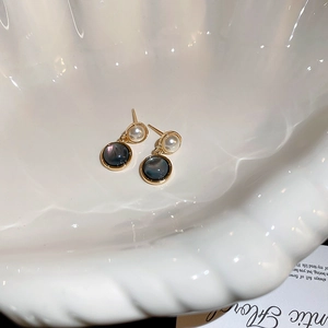 Close-up of vintage gold earrings with pearls and black shell in a shell tray