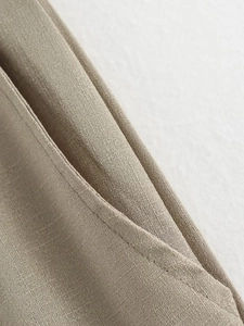 Close-up of khaki linen blend fabric showing weave texture and precise pocket stitching