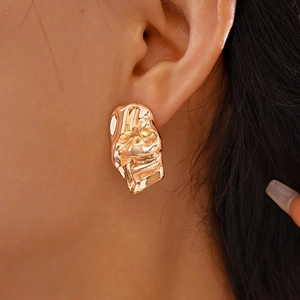 Detailed view of irregular molten texture gold earrings worn on a female model