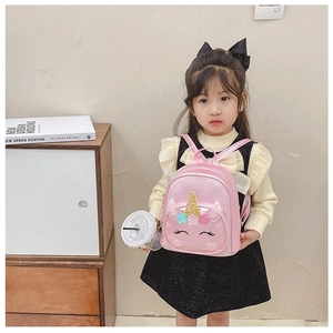 Close-up of cute pink unicorn backpack with glitter horn and embroidery on little girl