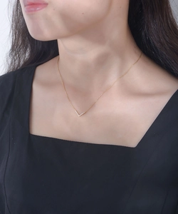 Close-up of a gold V-shaped necklace with crystals worn by a model on the neckline
