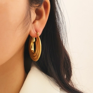 Close-up of gold layered hoop earrings on model featuring a chunky geometric design