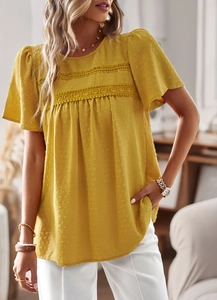 Detail view of ginger yellow round neck top with lace trim and dotted fabric texture