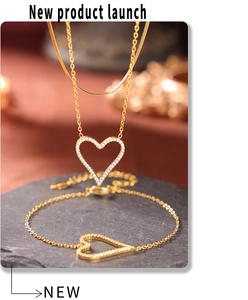 Close-up of gold heart-shaped necklace and bracelet set with micro-paved white zircons