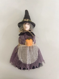 Detailed view of Halloween witch doll with purple dress and orange pumpkin decoration