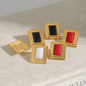 Macro shot of geometric gold stainless steel stud earrings in black, red, and white colors