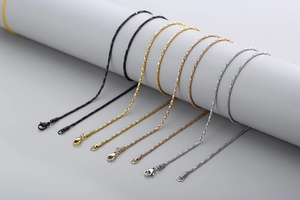 Detail of multiple metal necklace chains with lobster clasps on a white display stand