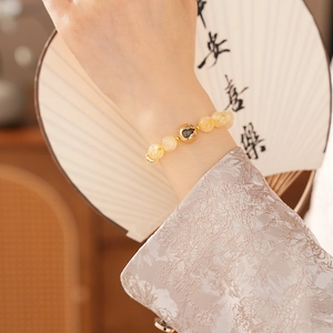 Macro view of citrine bead bracelet with gold heart charm on an elegant female wrist