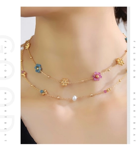 Detail of double-layer golden necklace with colorful flower pendants and white pearls