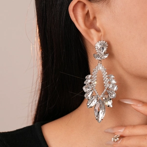 Detailed view of silver drop earrings with floral rhinestones worn by a model
