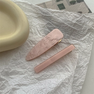 Detail of pink marble acrylic hair clips set with golden metal duckbill pins