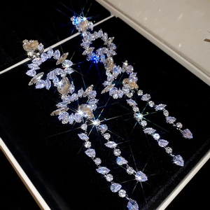 Detailed view of silver zircon tassel earrings with sparkling crystals on black velvet box
