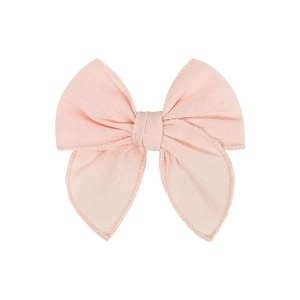 Detailed view of pink fabric bow hair clip with textured weave and fine stitching