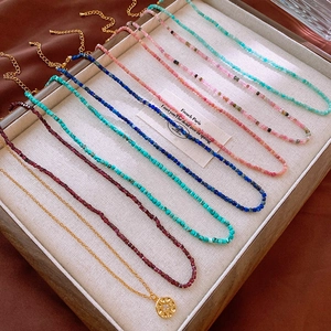 Close-up of colorful natural stone beaded necklaces and a vintage starburst gold pendant