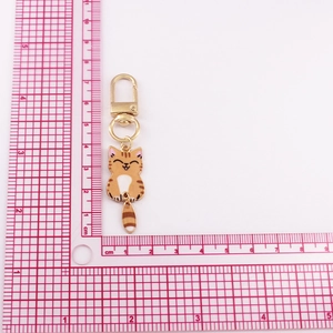 Mini cartoon cat keychain with orange stripes and movable tail on measurement background