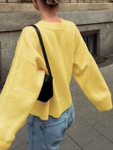 Außenaufnahme der Rückansicht einer Frau in einem lässigen gelben Strickpullover