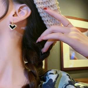 Detail of vintage heart drop earrings with black enamel and sparkling zircon on ear