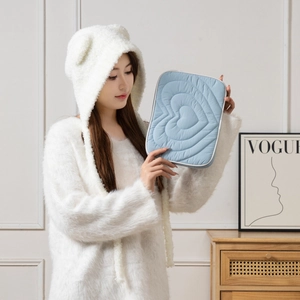 Quilted heart tablet sleeve in light blue being held in a stylish indoor setting