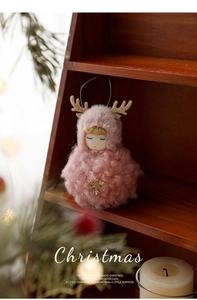 Detail of plush Christmas angel doll with deer antlers and golden snowflake on wood background