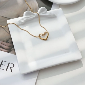 Elegante goldene Herzkette auf einer weißen Keramikschale mit Schleife dekoriert