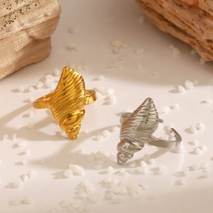 Golden and silver shell-shaped stainless steel rings on white stones for beach fashion
