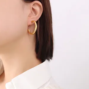 Minimalist 18K gold plated C-shaped chunky hoop earrings worn by a model in profile