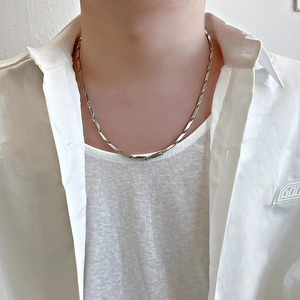 Close-up of a silver titanium steel melon seed chain necklace on a model wearing white