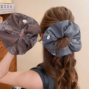 Detail of paisley pattern hair scrunchies on a high ponytail with button accents