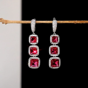 Macro detail of triple-layered square ruby drop earrings with sparkling micro-pave crystals